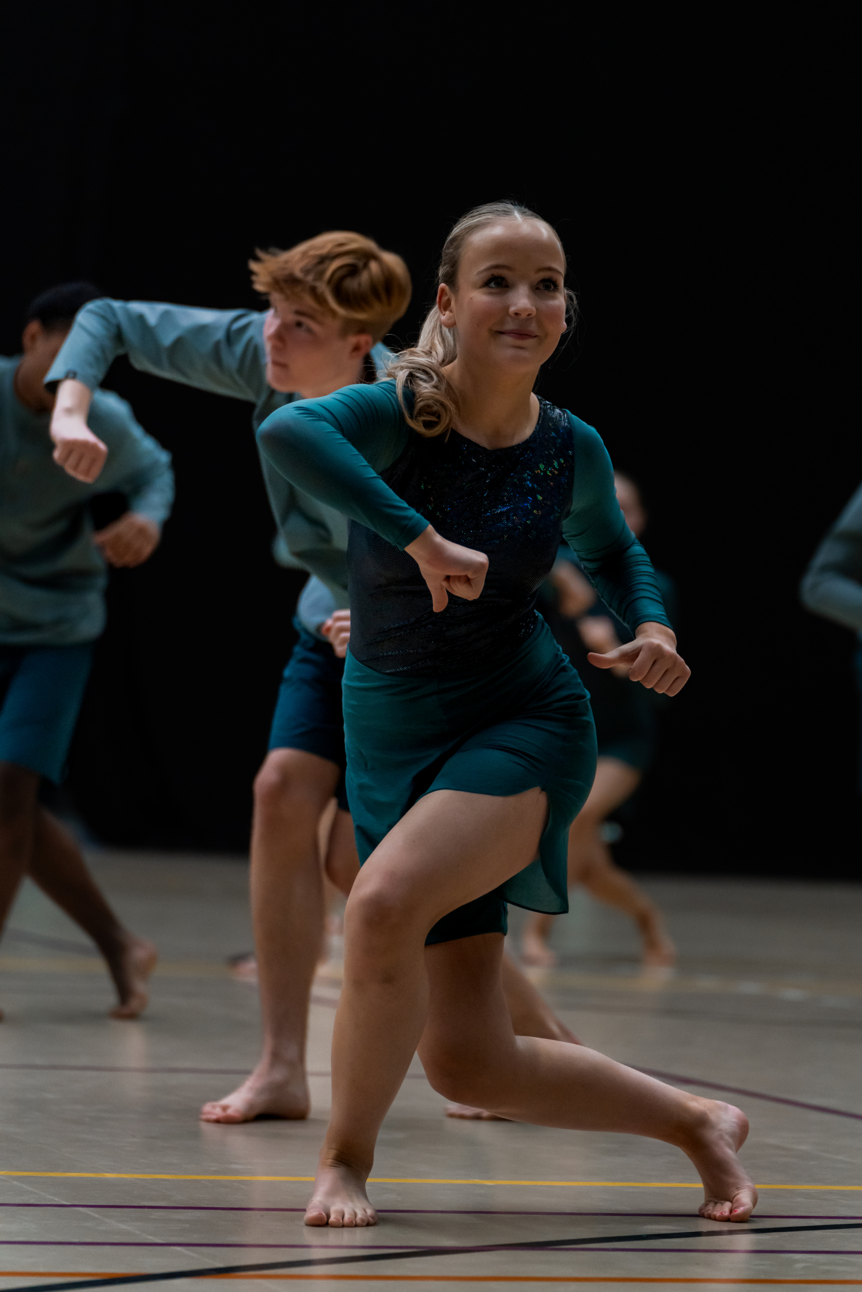 Billedet viser flere elever til en gymnastikopvisning. I forgrunden står en pige. Lige bag hende ses en dreng.